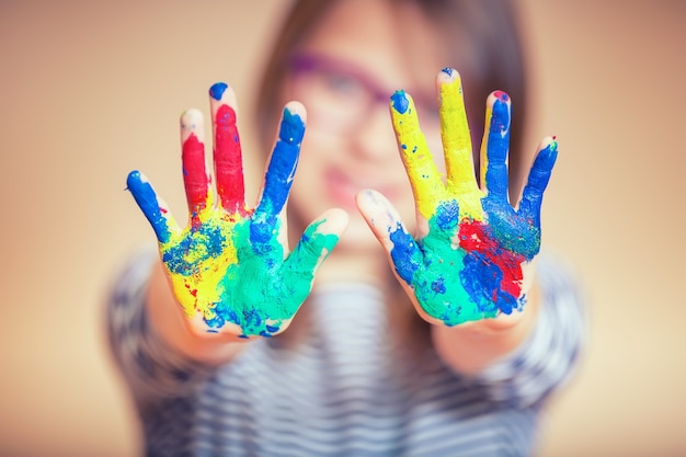 Portrait of a little pre-teen student girl showing painted hands. Toned Photo.