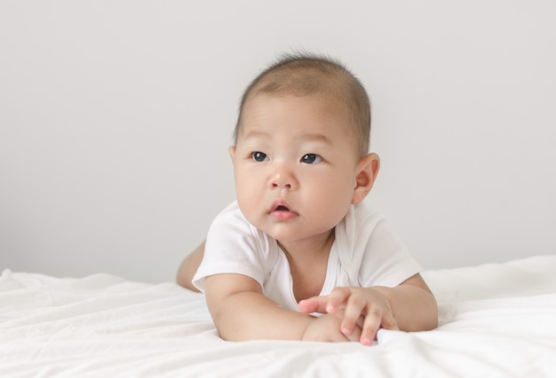 Portrait of little small asian baby infant laying on bed looking up