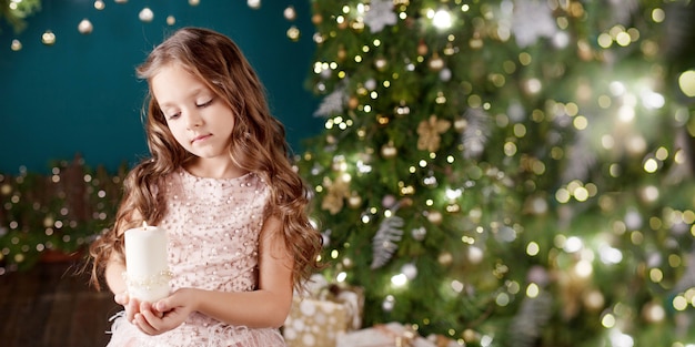 Portrait of long-haired little girl in dress on background of  lights.