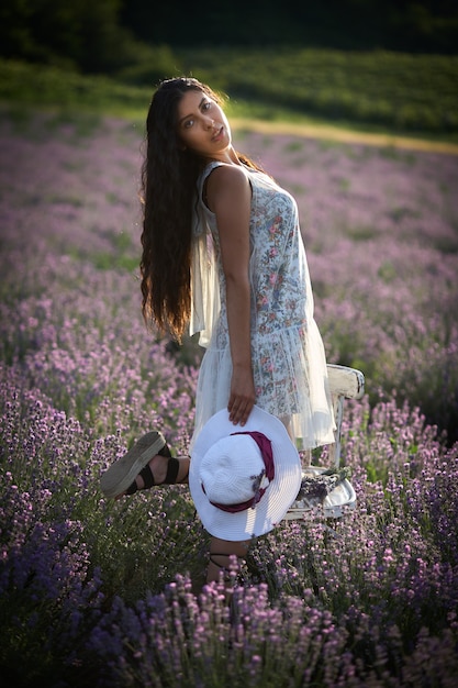 Photo portrait of lovely brunette girl with hat on lavender field background.