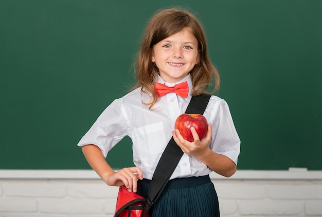 Portrait of lovely girl wuth red apple in classroom Education learning and children concept