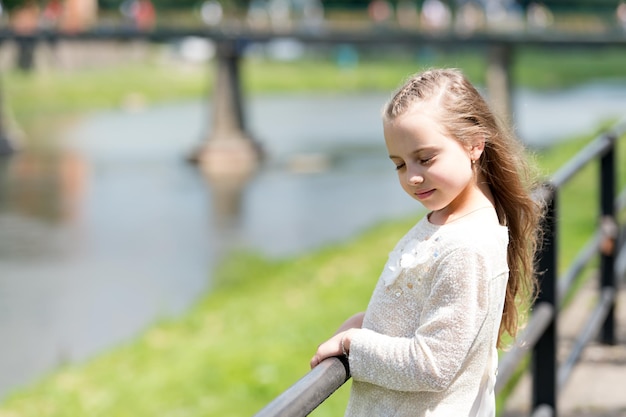 Portrait of a lovely little happy cute princess girl with long blonde curly hair at summer sunny day