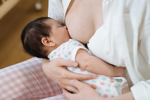 portrait of lovely newborn nestling up to her mother having breast milk. newborn care, nurturing and health concept.