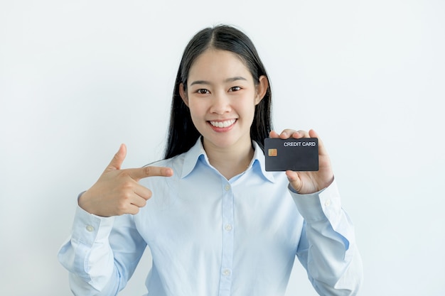 Portrait of a lovely young Asian beautiful woman with long hair holding a blue credit card, her eyes sparklingly at the camera. Ready to pay shopping according to discounted products.