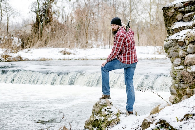 Portrait of a lumberjack with an ax on the background of the river in the spring