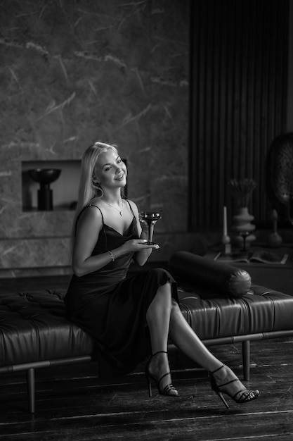 Portrait of a luxurious young blonde woman in a black sexy dress In a dark interior