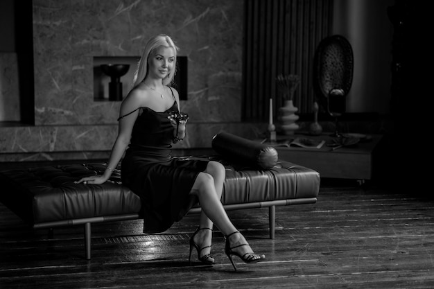 Portrait of a luxurious young blonde woman in a black sexy dress In a dark interior