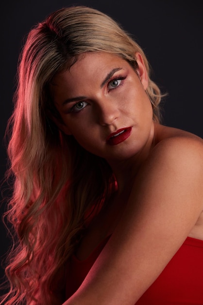 Portrait luxury and makeup with a model woman in studio on a dark background in red lighting for desire Face beauty or skincare with a young female person posing for natural feminine confidence