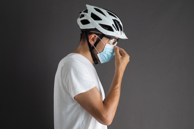 Portrait of a Male Cyclist Puts On a Protective Mask on His Face.