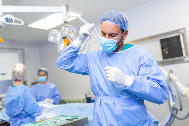 Portrait of male doctor surgeon taking off medical mask standing in operation room Surgeon at modern operating room