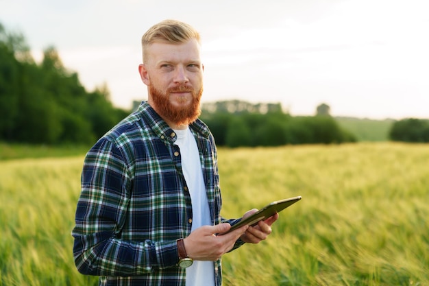 Portrait of a male farmer with a tablet that stands in a wheat field Good ecological farm harvest