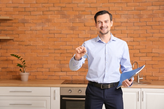 Portrait of male real estate agent with key indoors