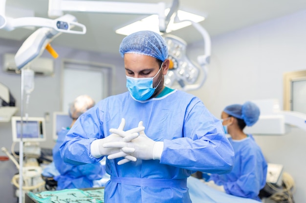 Portrait of male surgeon with team of doctors on background in operation room