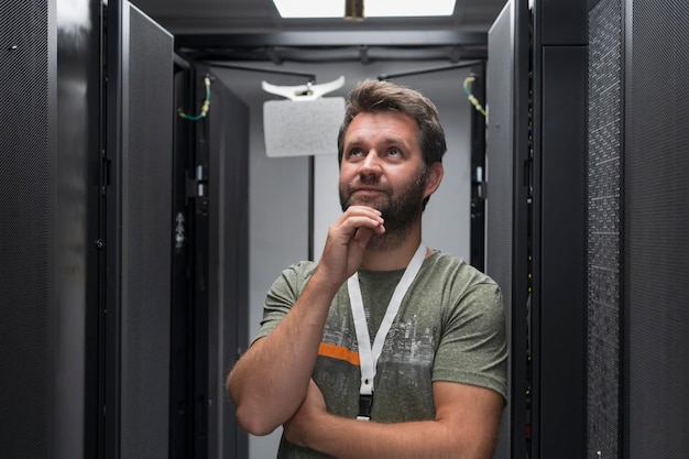 Photo portrait of male technician or network administrator standing brave as a hero with arms crossed in data center server room. high quality photo