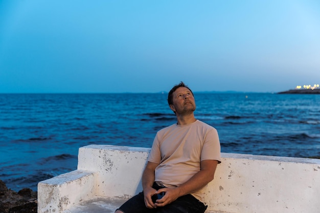 Portrait of a man against the backdrop of the sea on a summer evening