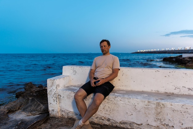 Portrait of a man against the backdrop of the sea on a summer evening