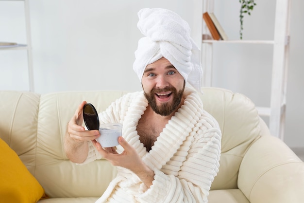 Portrait of man applying effective cream on his facial skin. Spa at home, body and skin care for male concept.