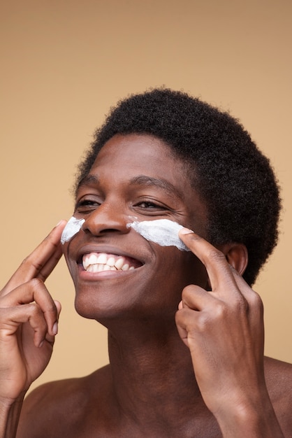 Portrait of a man applying moisturizer on his face