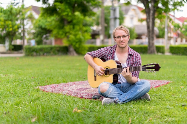 Portrait of man having picnic while playing the guitar outdoors