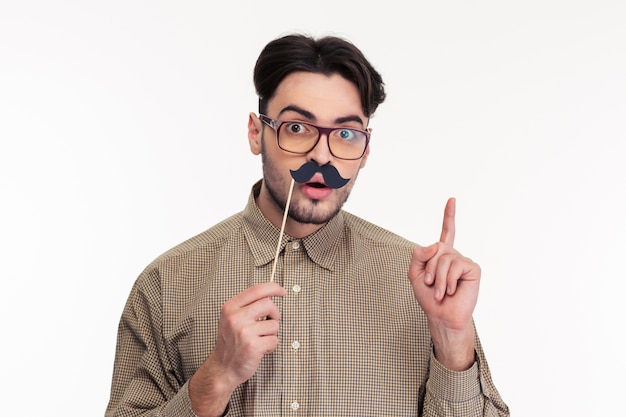 Portrait of a man holding stick with mustache and pointing finger up isolated on a white wall