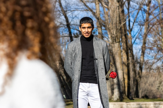 Portrait of a man in love with a rose for his girlfriend Young man in love hiding a rose for his girlfriend outdoors