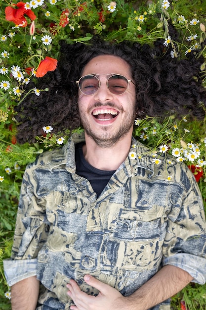 Portrait of a man lying on the grass in a field of poppies and daisies