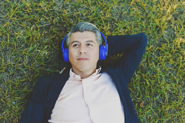 Portrait of a man lying on the grass listening to music with headphones