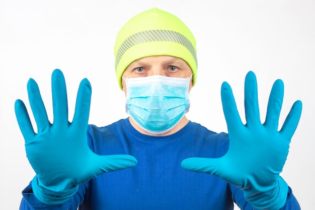 Portrait of a man in a medical mask with raised hands in protective gloves