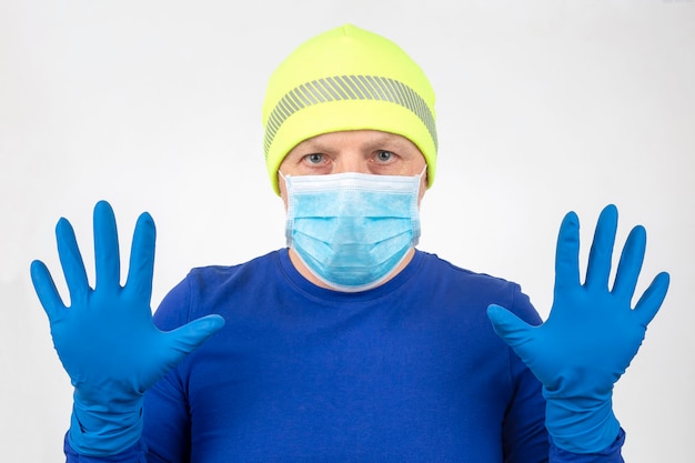 Portrait of a man in a medical mask with raised hands in protective gloves