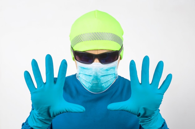 Photo portrait of a man in a medical mask with raised hands in protective gloves