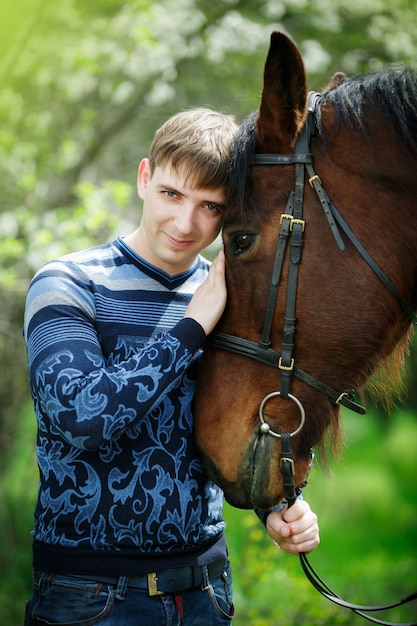 Portrait of the man near a brown horse