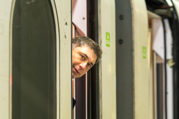 Photo portrait of man peeking from train window