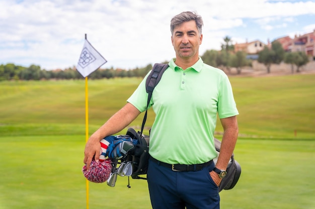 Portrait of a man playing golf together with the clubs on the green enjoying the sport