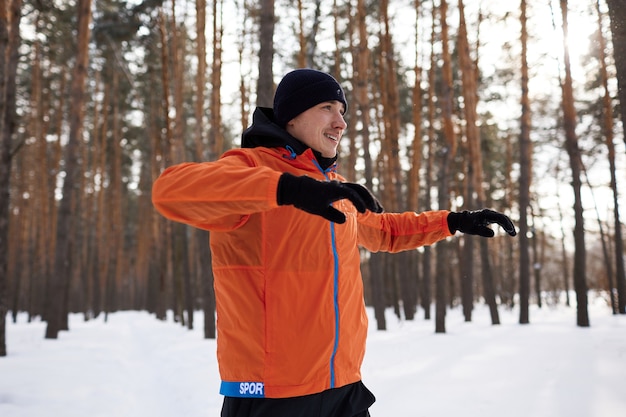 Portrait of a man stretching in the park on a beautiful snowy winter day, preparing for running