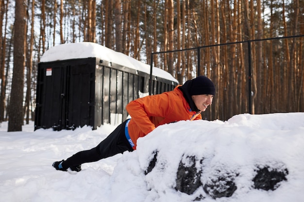 Portrait of a man stretching in the park on a beautiful snowy winter day, preparing for running