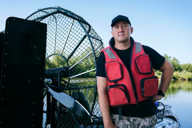 Portrait of a man on vacation in nature riding an airboat on the river in hunter's clothes