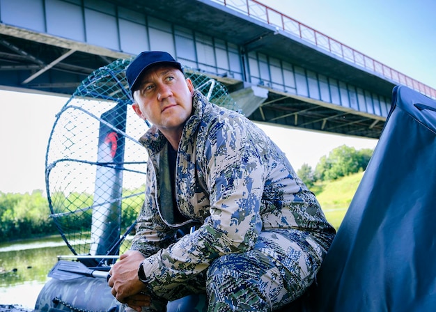 Portrait of a man on vacation in nature riding an airboat on the river in hunter's clothes