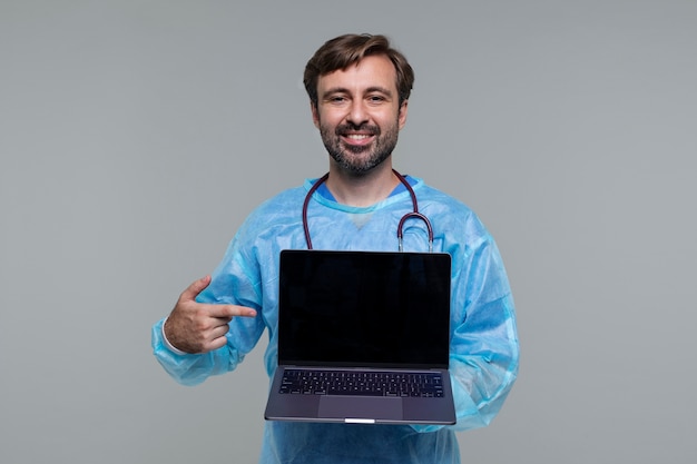 Portrait of man wearing medical gown and holding laptop