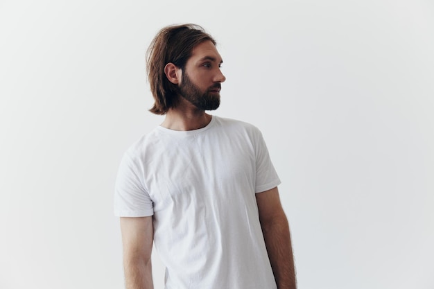 Portrait of a man with a black thick beard and long hair in a white Tshirt on a white isolated background emotion of sadness and longing