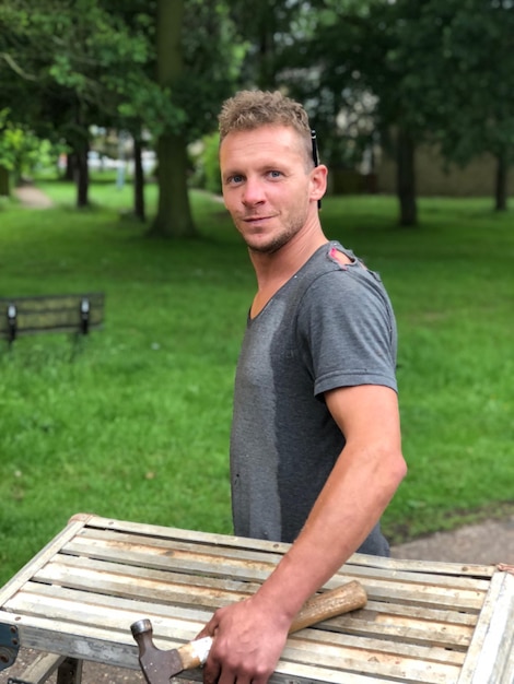 Photo portrait of man with hammer at park bench