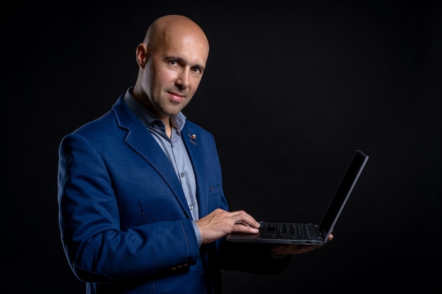 Portrait of man with laptop in studio on black background