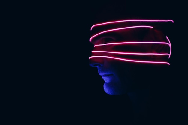 Portrait of man with neon glow lines on his face Concept cyberpunk and virtual reality