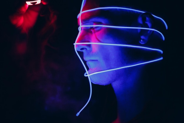 Portrait of man with neon glow tube lines on his face in dark Concept cyberpunk and virtual reality