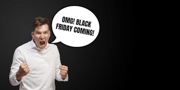 Portrait of man with speech bubble on black studio background. Copyspace for your advertising. Black friday, cyber monday, sales, money and cash, online purchases and payments concept. Crazy calling.