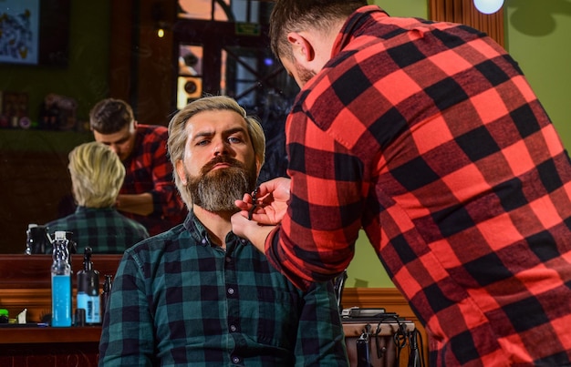 Portrait of masculinity master barber does the hairstyle and styling with dryer Barbershop Young