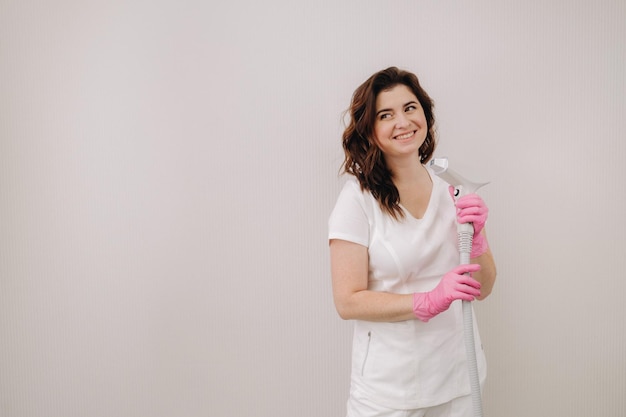 Portrait of the master of laser hair removal A woman in a white coat holds a laser hair removal device in her hands