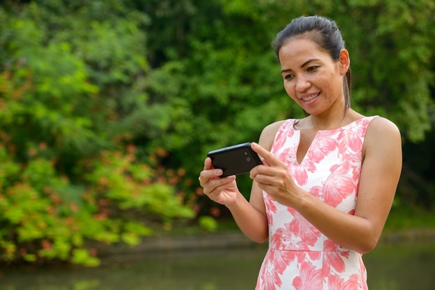 Portrait of mature Asian woman relaxing at the park outdoors