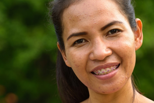 Portrait of mature Asian woman relaxing at the park outdoors