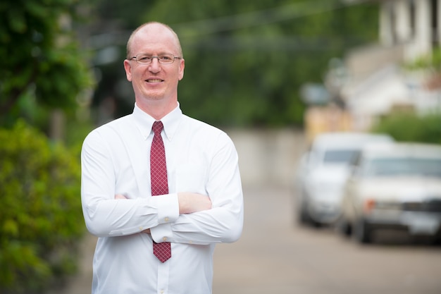 Portrait of mature bald businessman wearing shirt and tie in the streets outdoors