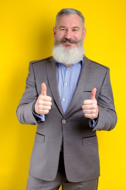 Portrait of mature businessman dressed in gray suit shows thumbs up